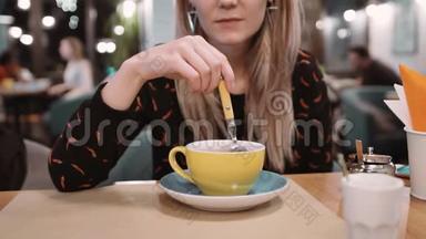 一个女人在餐馆里用勺子在杯子里搅拌糖。 慢动作